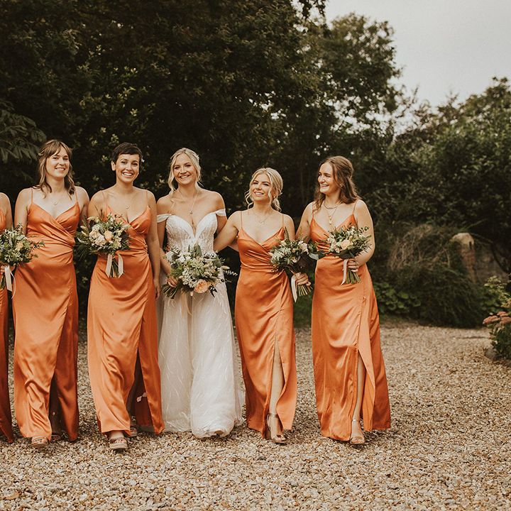 Bridesmaids in orange wrap dresses for summer wedding