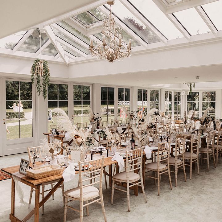 Wedding reception complete with white chairs and open vibe with dried floral arrangements