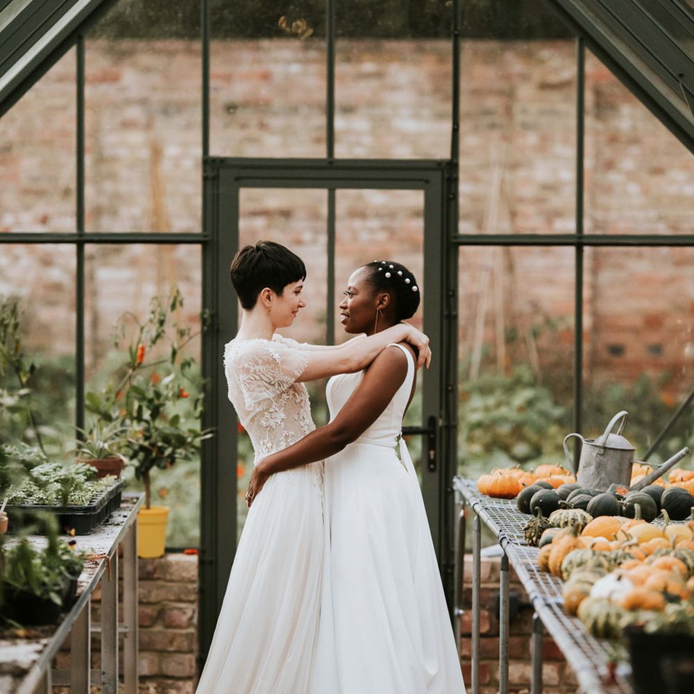 Autumn wedding with a bride with short hair in a romantic wedding dress embracing her Black bride in a minimalist wedding dress 