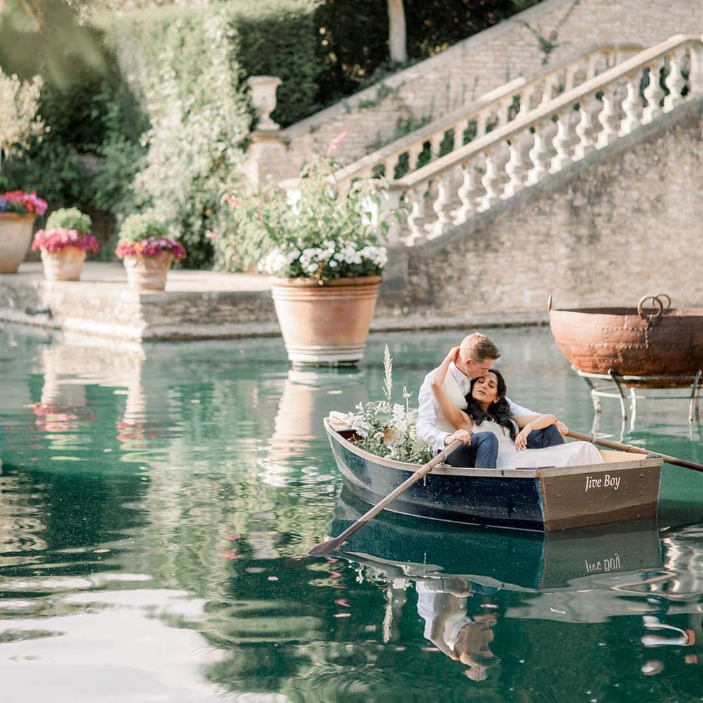 Bride & groom in canoe pictured on sparkling blue water 