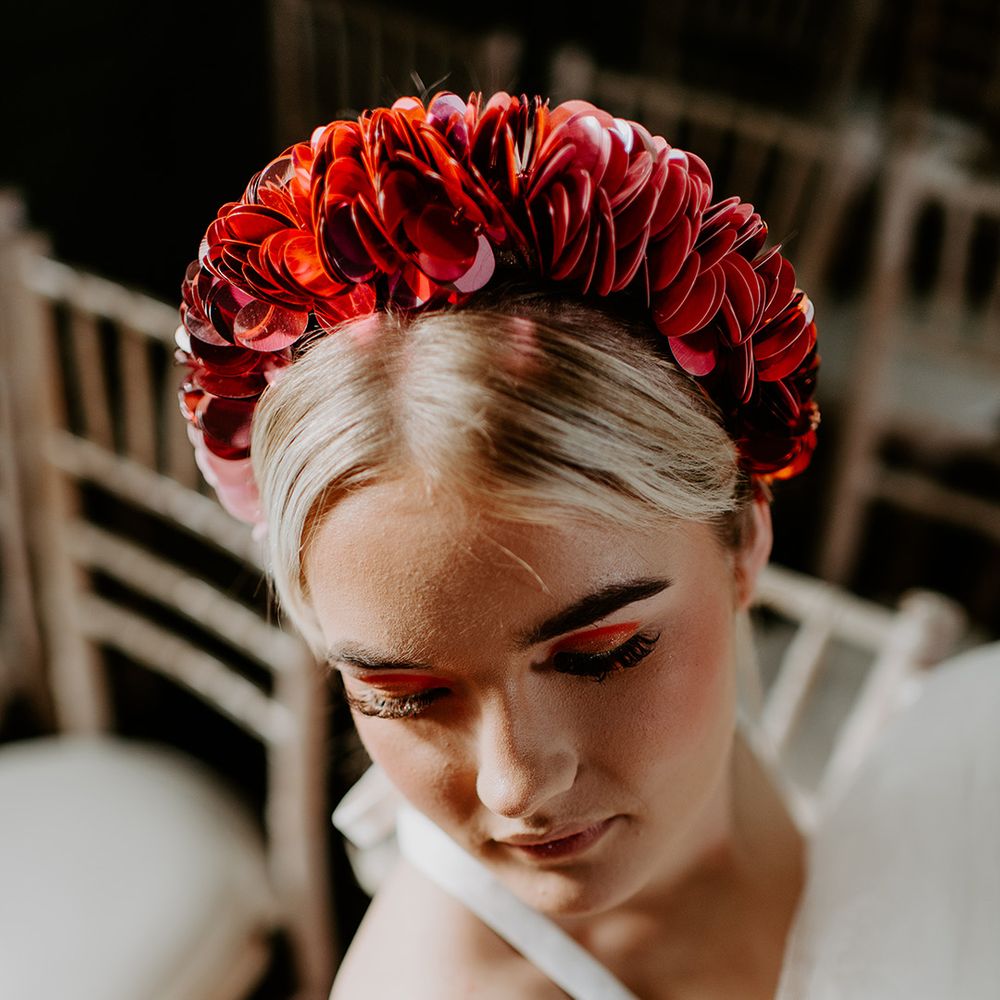 Bride with orange eyeshadow and long eyelashes wearing a red applique headdress 