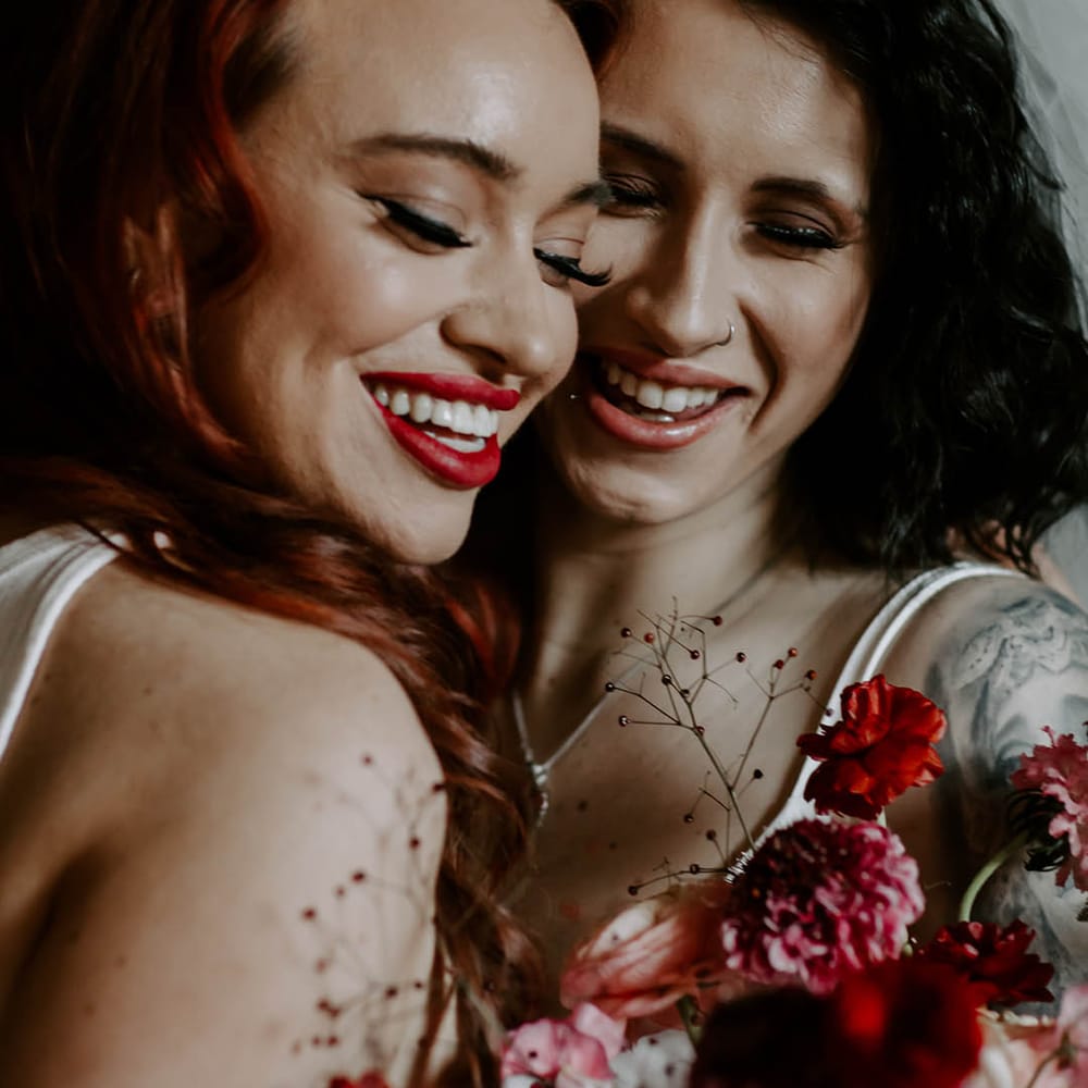 Intimate photo of an LGBTQI couple with winged eyeliner and bold red lipstick