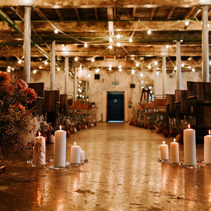 Aisle style with candles and warm toned flowers for industrial wedding venue