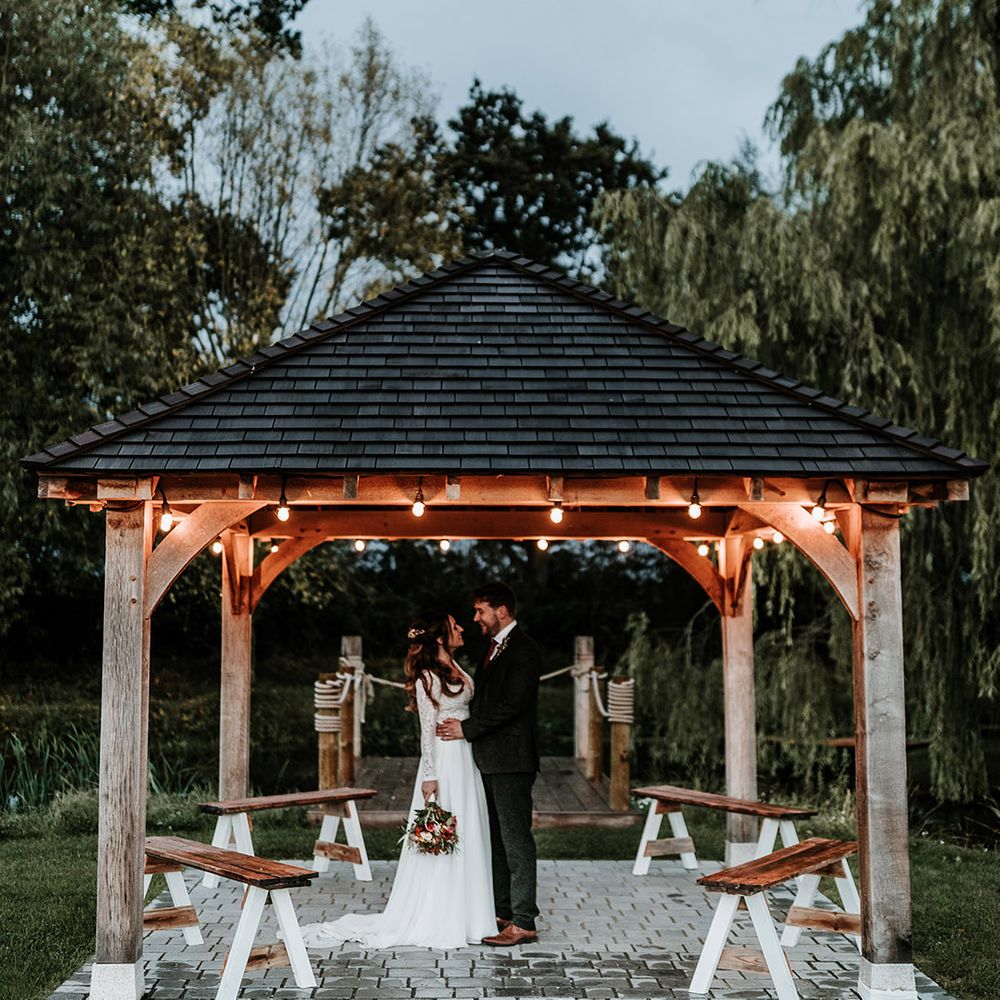 Bride and groom stand under gazebo after their wedding ceremony 