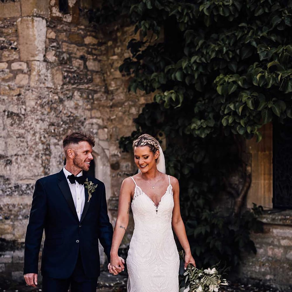 Bride and groom walk with their hands intertwined for their summer outdoor wedding 