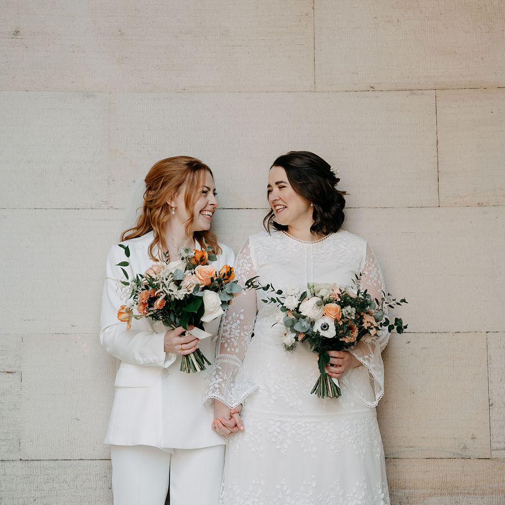 Brides stand together holding bright floral bouquets for intimate and relaxed wedding day
