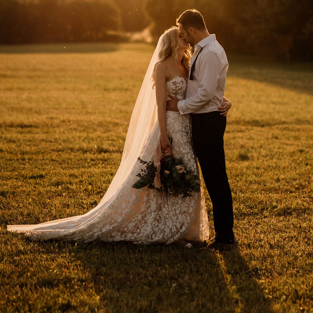 Bride and groom share a kiss as golden hour hits for beautiful couple portrait 