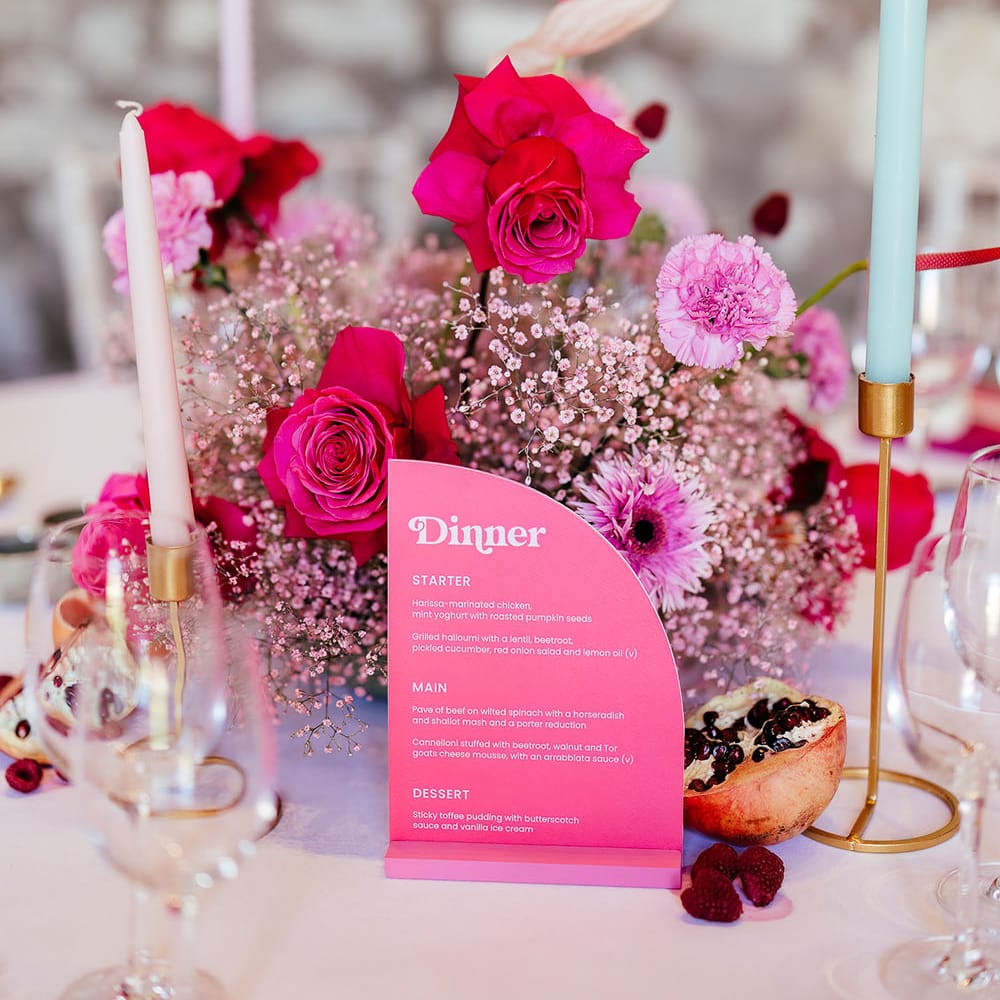 Bright pink floral centrepiece for modern tablescape complete with pastel coloured candles and dried fruit decor 