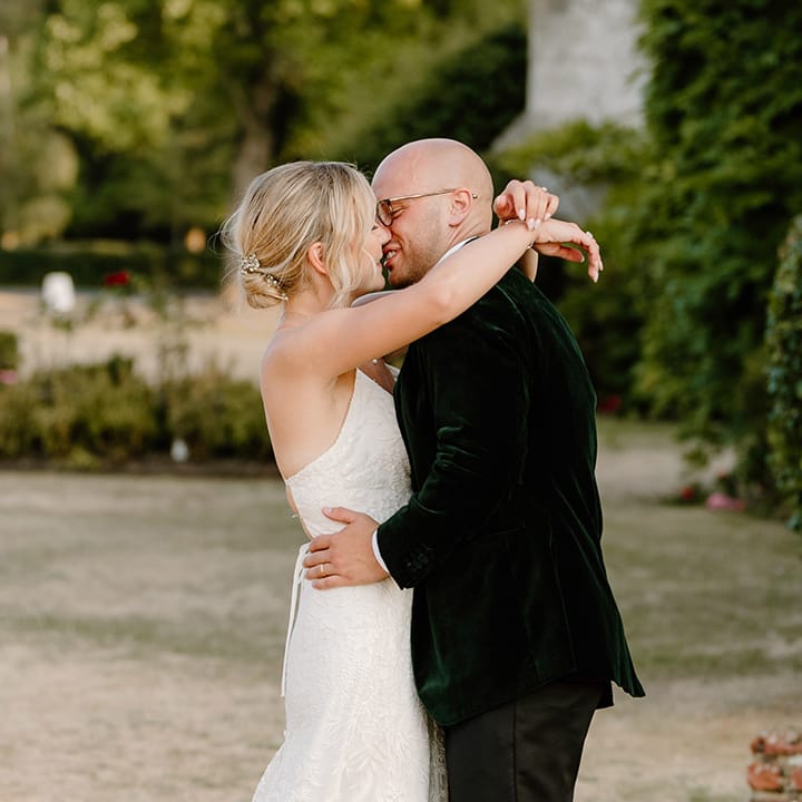 Bride & groom kiss outdoors at Bisham Abbey during summer wedding with Krispy Kreme doughnut tower