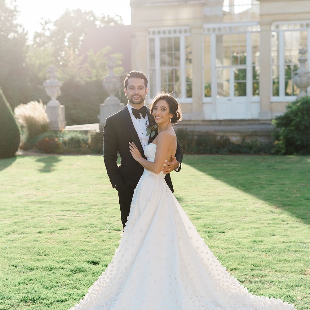 Bride wears Emma Beaumont bespoke wedding dress and stands with her groom in black tie 