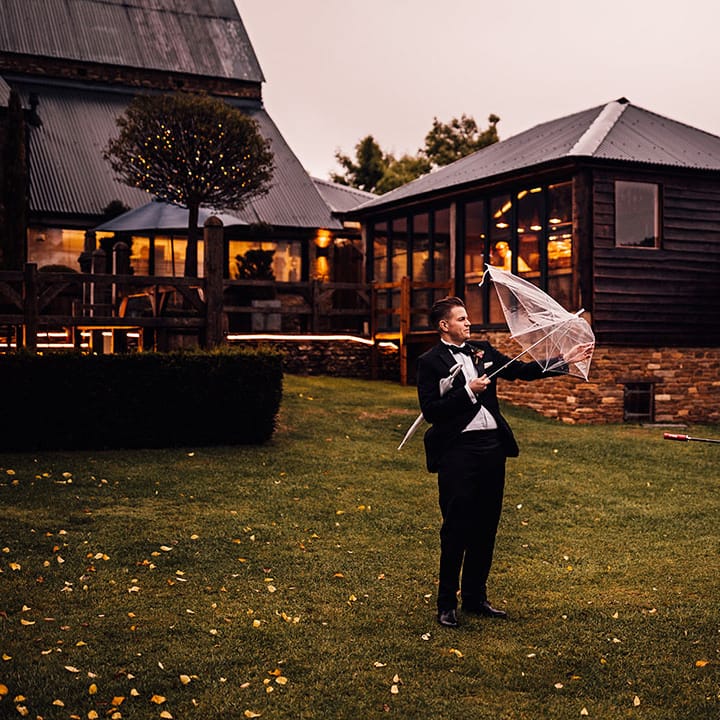 Wedding guests have struggles opening umbrellas on the windy and rainy day 