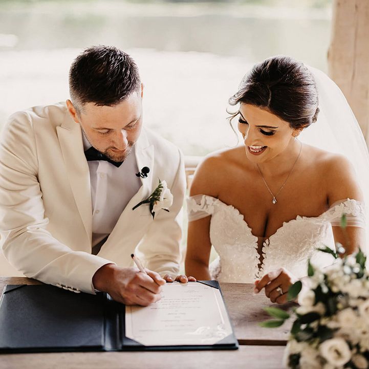 The bride and groom sign their wedding register after their outdoor ceremony 