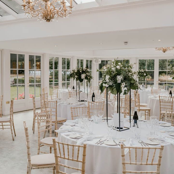 Tall white flower wedding table flower centrepieces with black metal on all white table wedding setting 