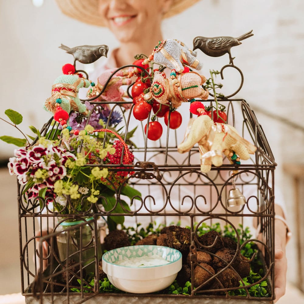 Unique and unusual display of wedding food with falafel and hummus in a birdcage decorated with flowers 