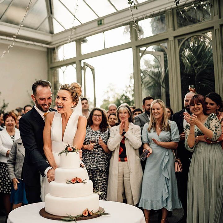 The bride and groom cut their classic white wedding cake with four tiers and figs 