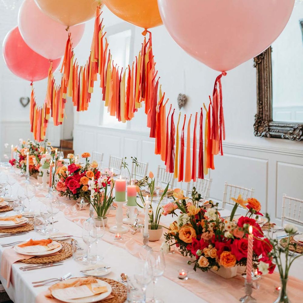 Merriscourt wedding with wedding tablescape with white wedding tablecloth, burlap place mats, tapered candles, pink and orange wedding stationery, and floral wedding table centrepieces with pink and orange garden roses, orange floribunda, yellow ranunculus flowers, foliage and Iceland poppies with red, pink orange and yellow balloons, wedding streamers and fairy lights