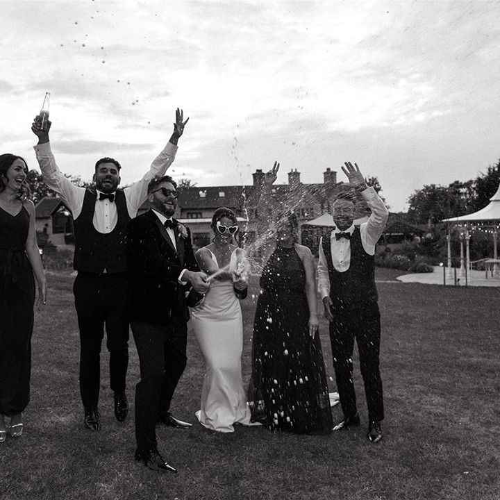 Champagne pop wedding photo of the wedding party celebrating the day 