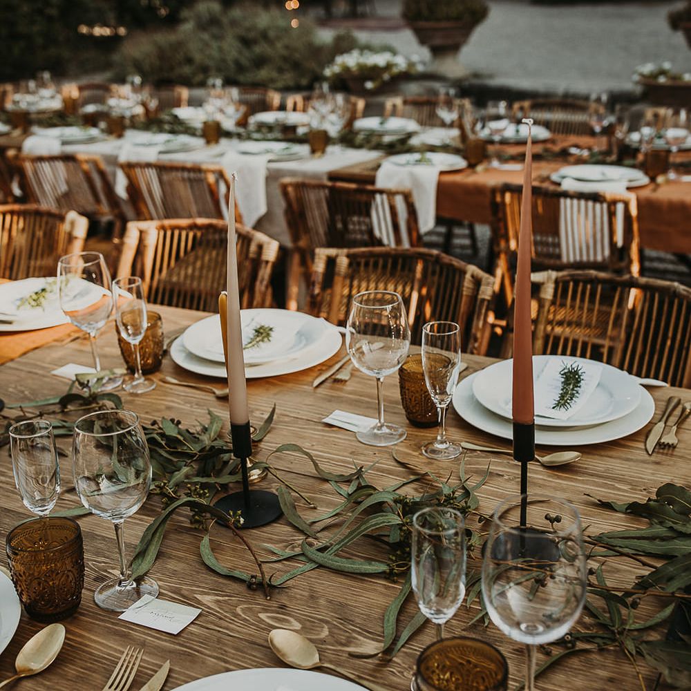 Wooden table, coloured taper candles and olive branch table runner 