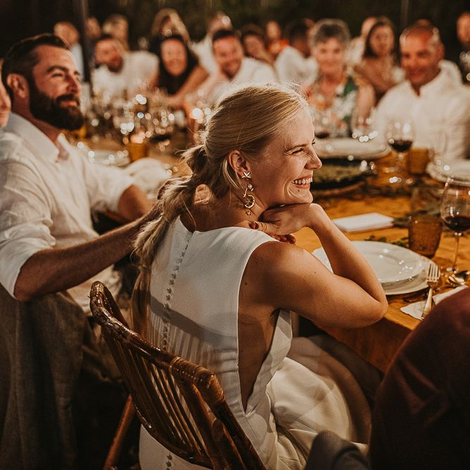 Bride with fishtail braid smiling during the festoon lit reception 