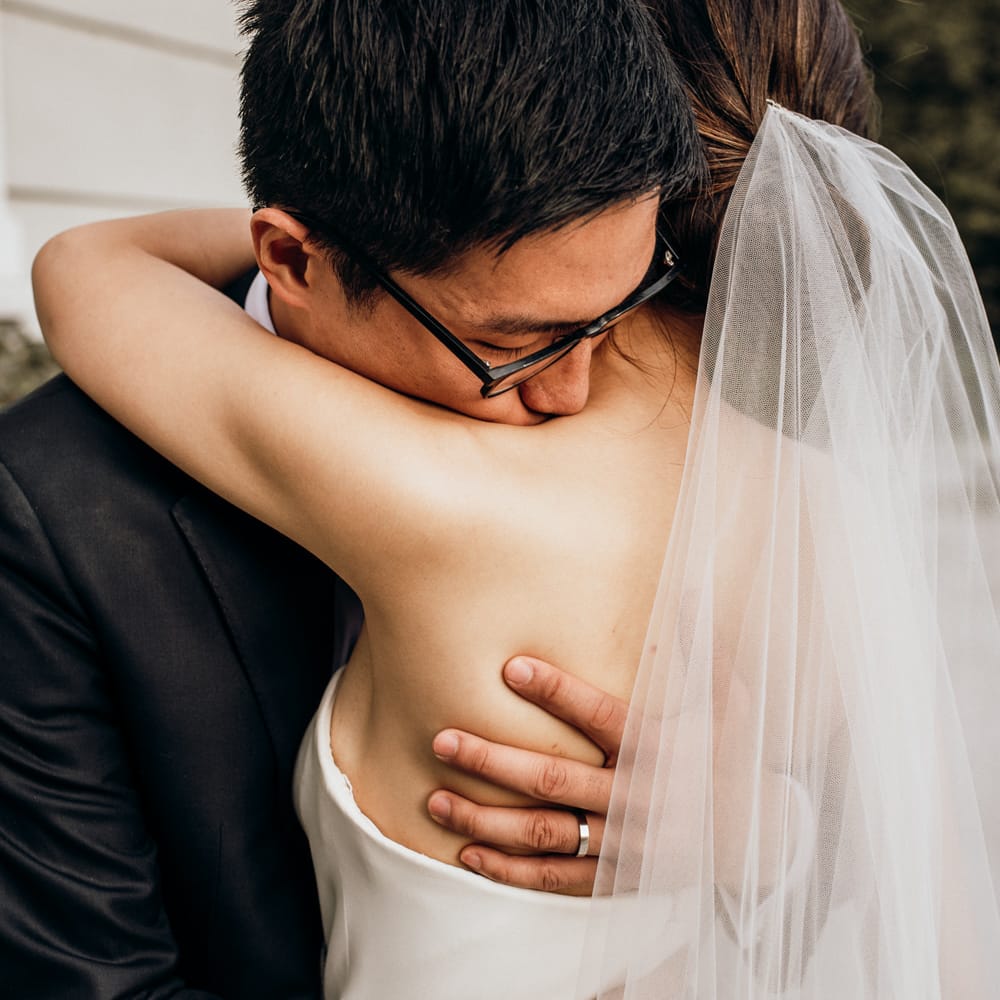 Intimate wedding portrait of the groom embracing his bride 