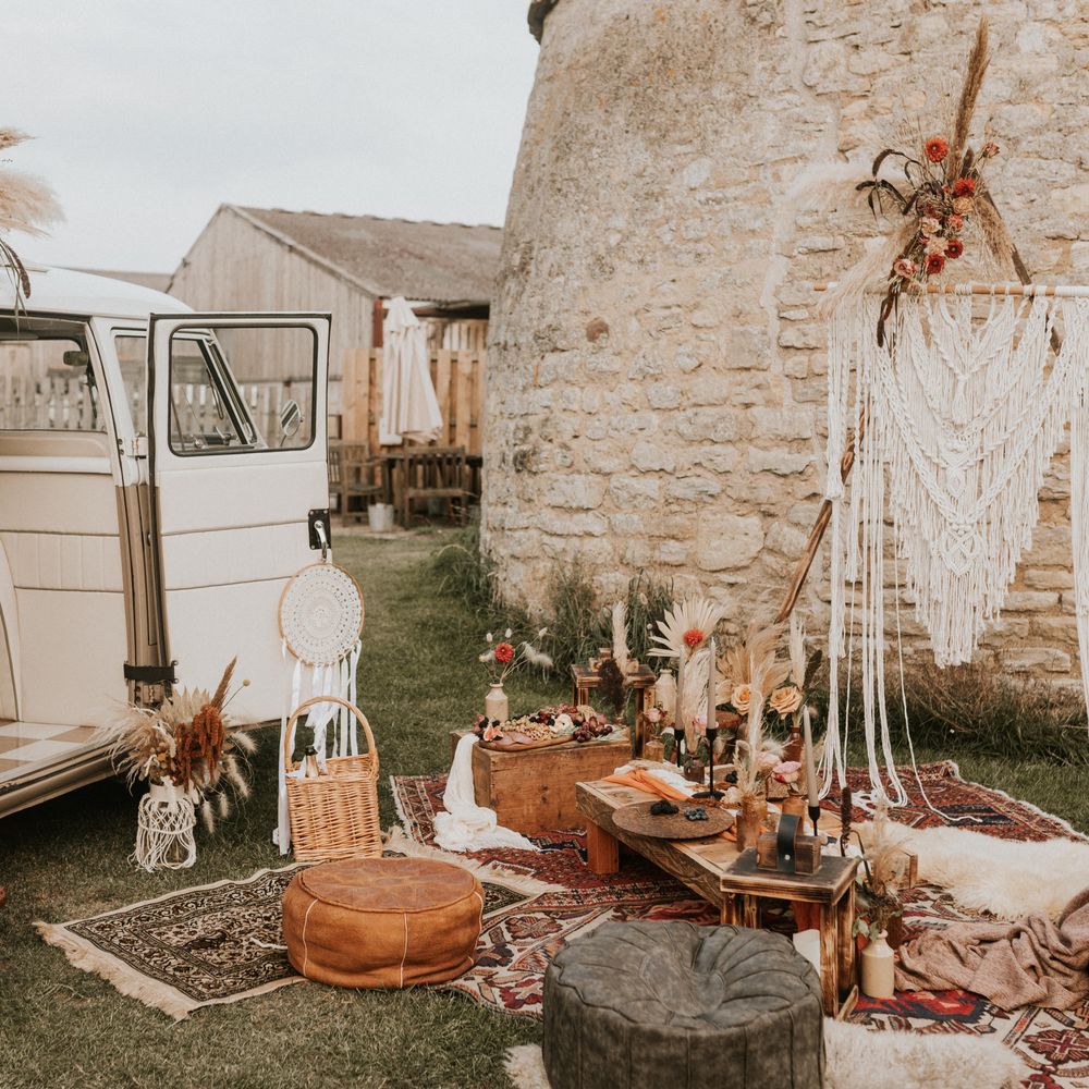 Camper van next to Macrame backdrop with wooden tables and trunks with grazing plates