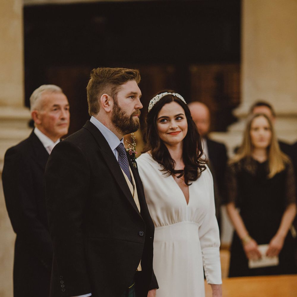 Bride and groom holding hands at London wedding ceremony bride looking lovingly at groom