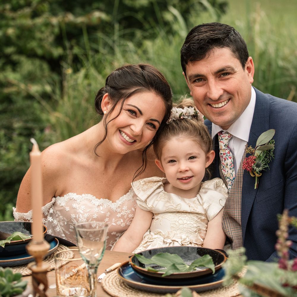Bride & groom sit together with little during vow renewal dinner