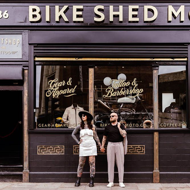 Alternative bride and groom standing outside a tattoo parlour at micro wedding 