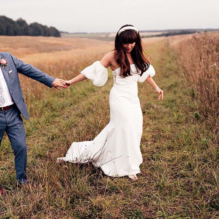 Bride & groom walk along fields in the countryside on their wedding day