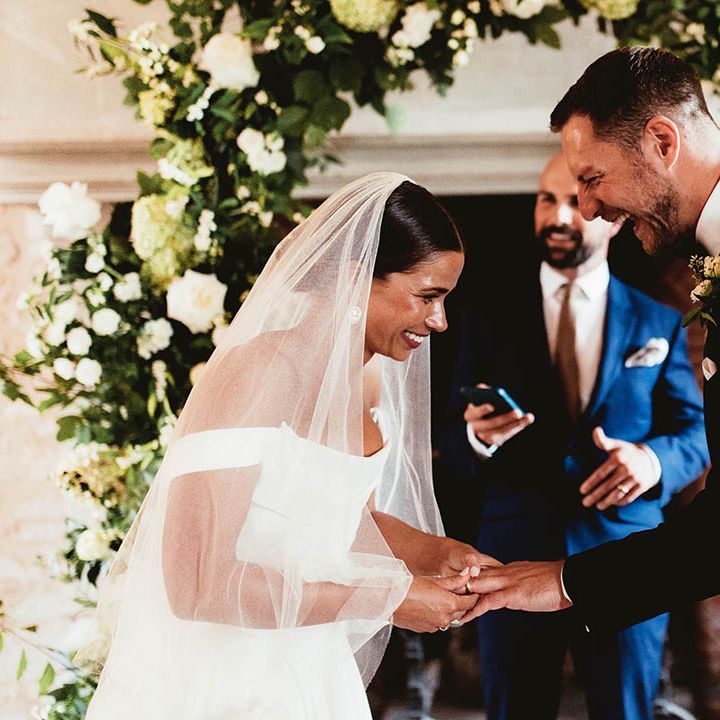 Bride & groom hold hands on their wedding day in front of florals