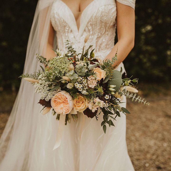 Bride clutches peach bouquet in off the shoulder wedding dress