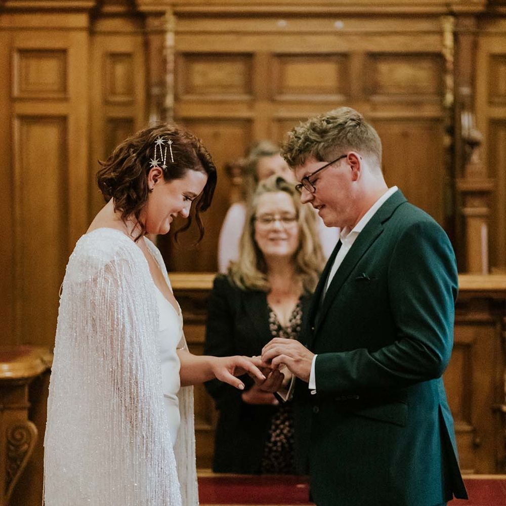 Groom places ring on his brides finger during wedding ceremony
