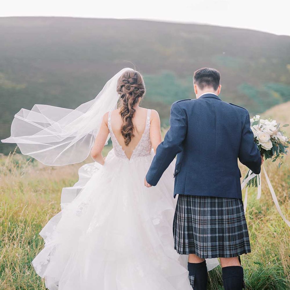 Drumtochty Castle wedding with groom in a blue tartan kilt and jacket and bride in a Martina Liana princess wedding dress with long plated hair