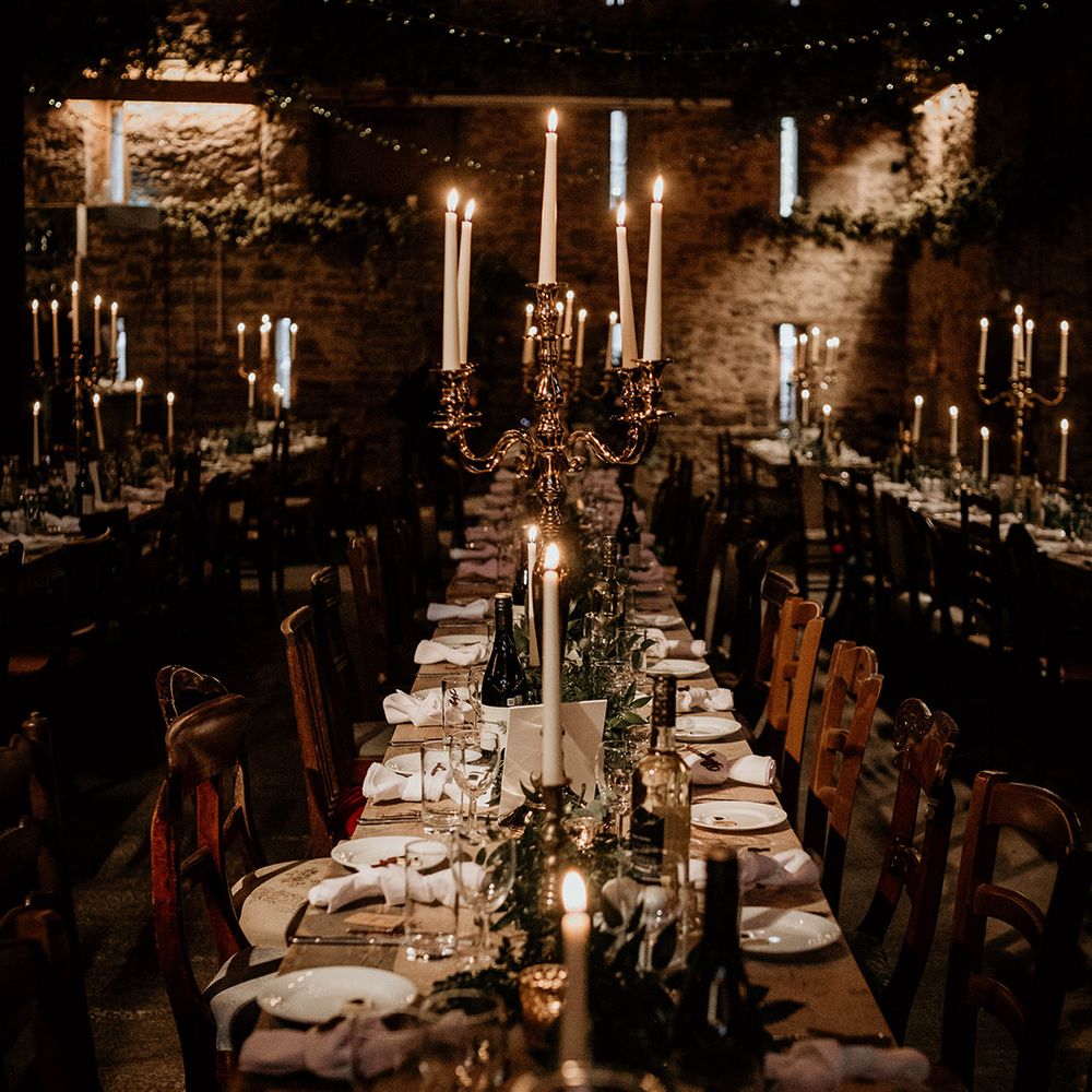 Stone barn wedding reception at Lyde court decorated with candelabras and taper candles 