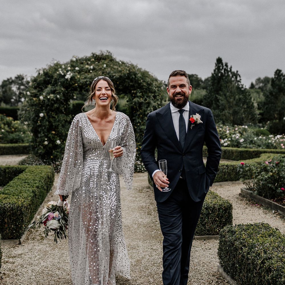 back garden wedding with bride in a silver sequin wedding dress and bridal crown, and groom in a navy suit 