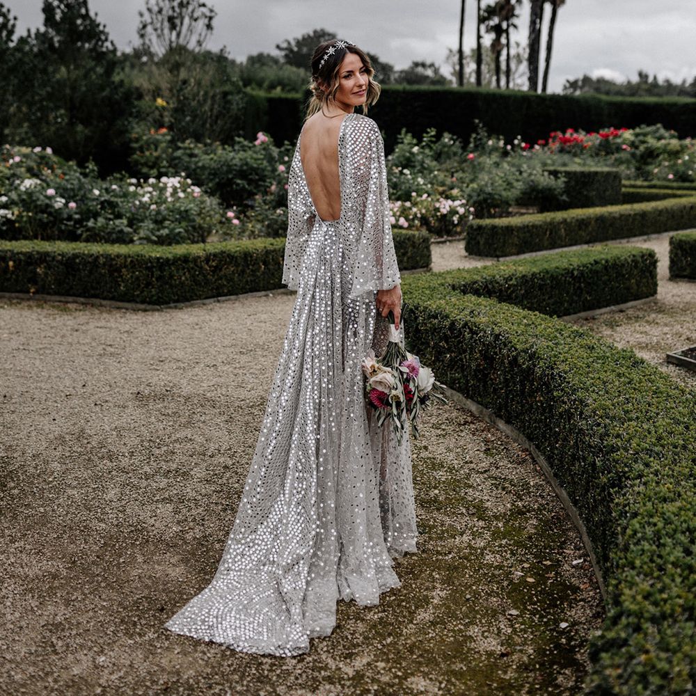 Bride in a sparkly silver wedding dress with low back detail at her outdoor tipi wedding 