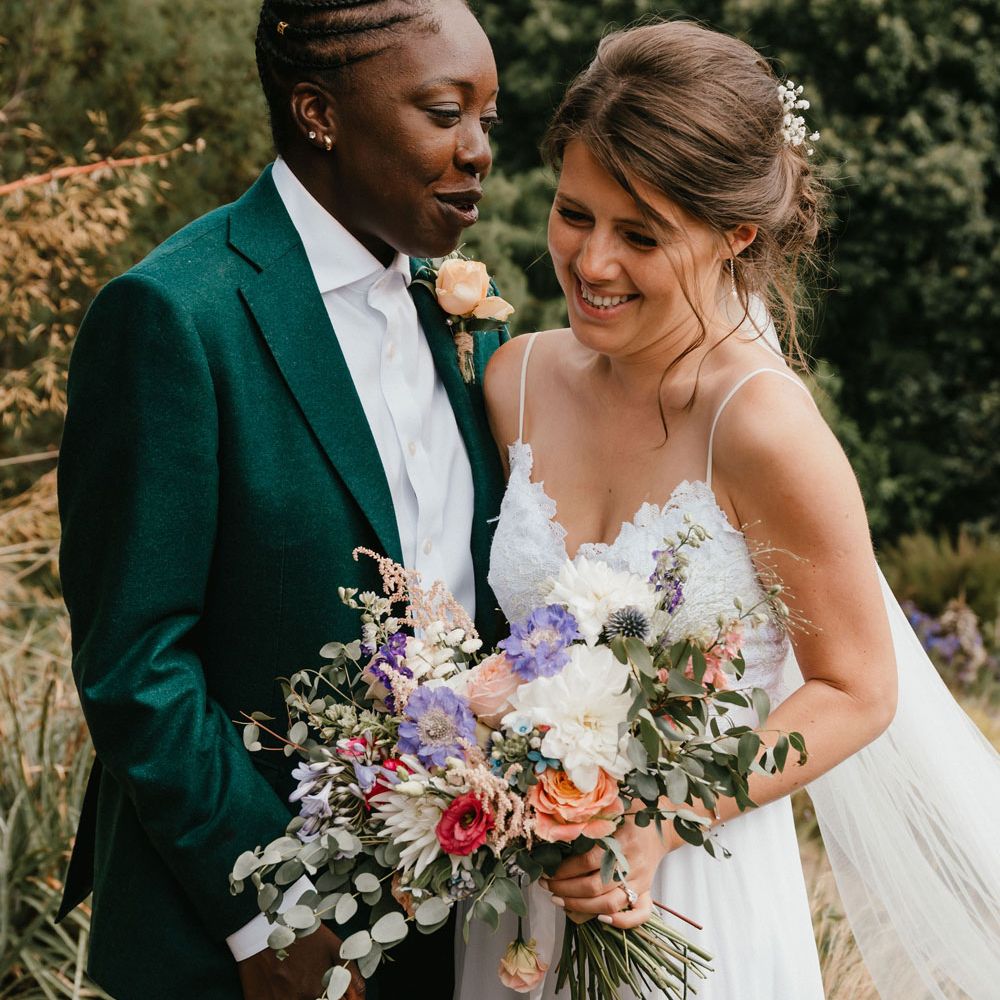 Intimate couples portrait at LGBTQI+ wedding with two brides in a green suit and boho wedding dress