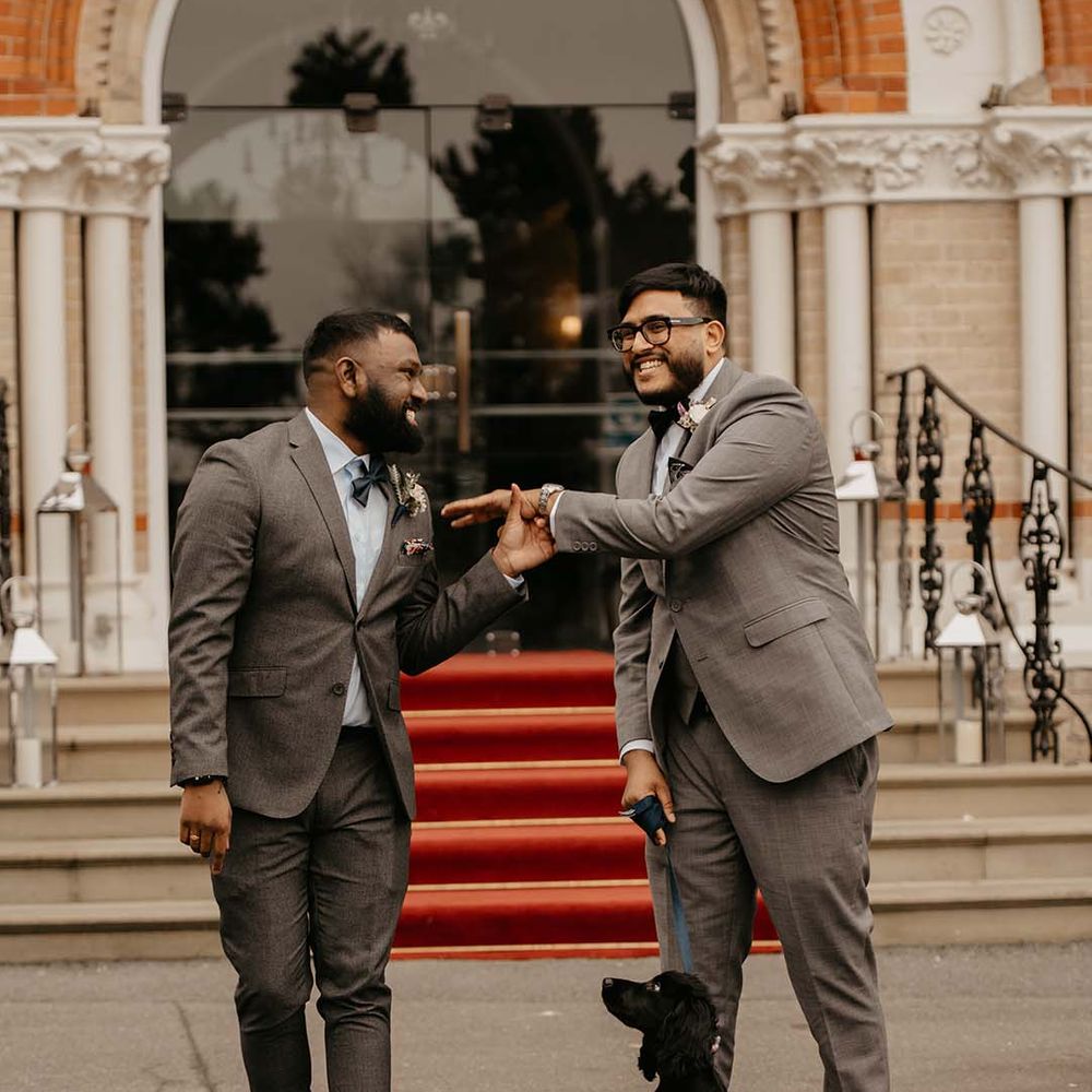 Groom and groomsman in grey suit and bow ties with boutonnières  
