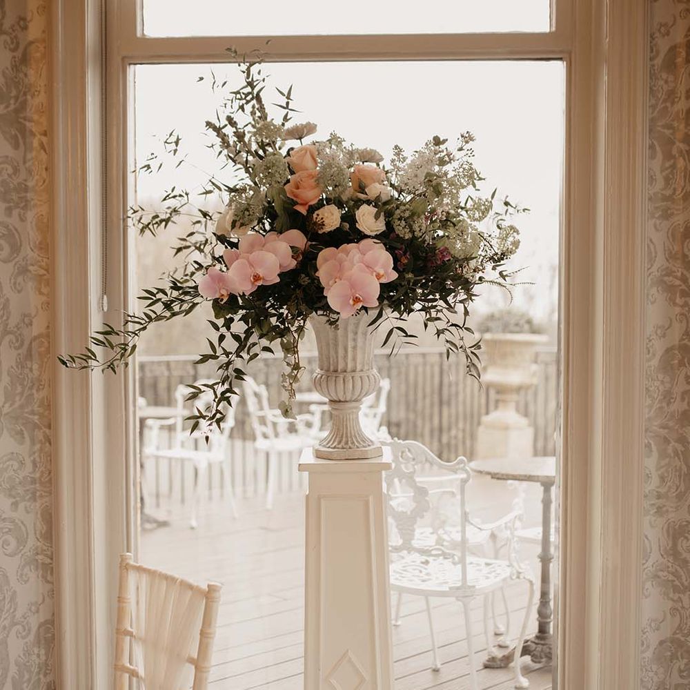 Pink, white, red and green mixed floral display in large white ceramic vase 