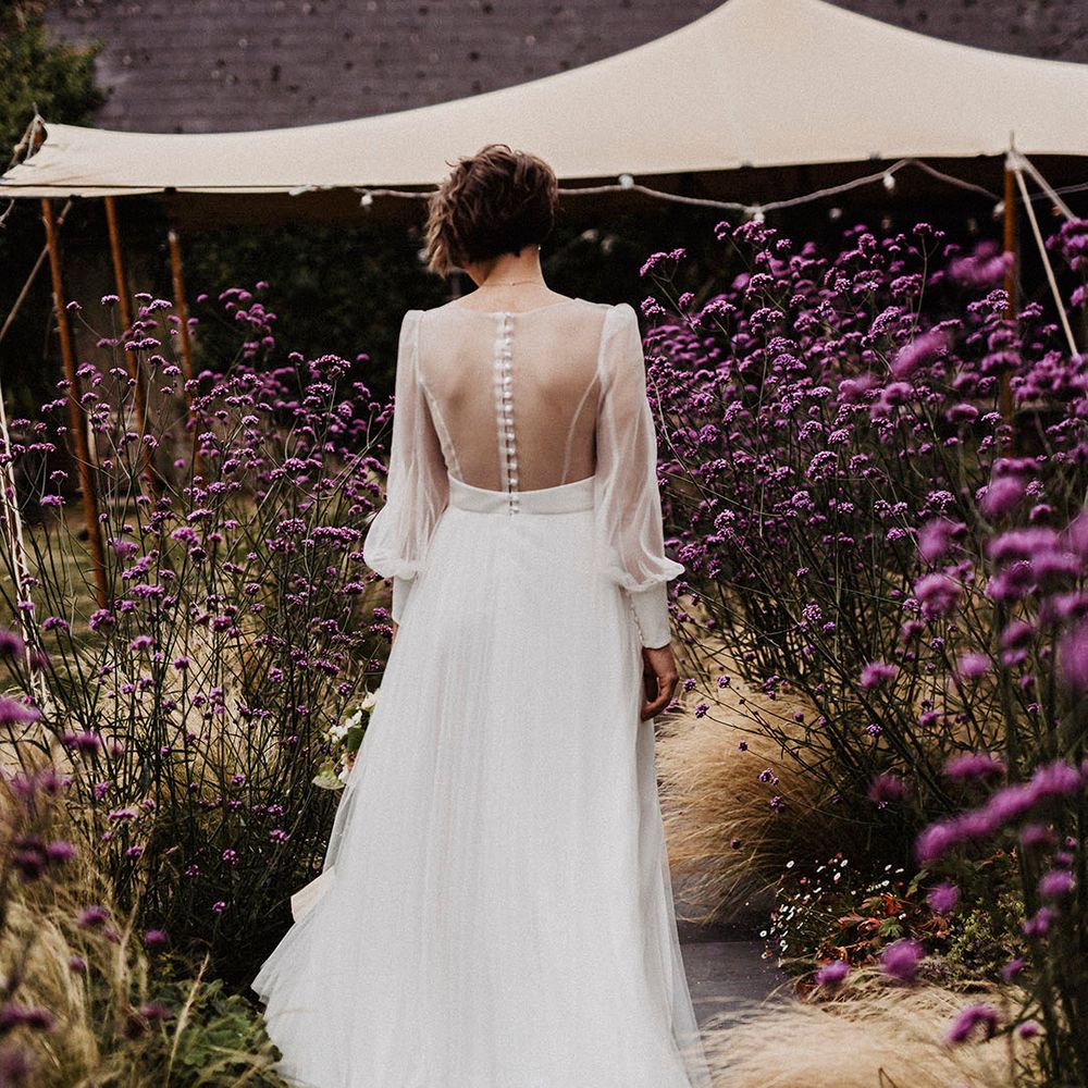 Bride in wedding dress with sheer back and sleeves with button detail and tulle skirt
