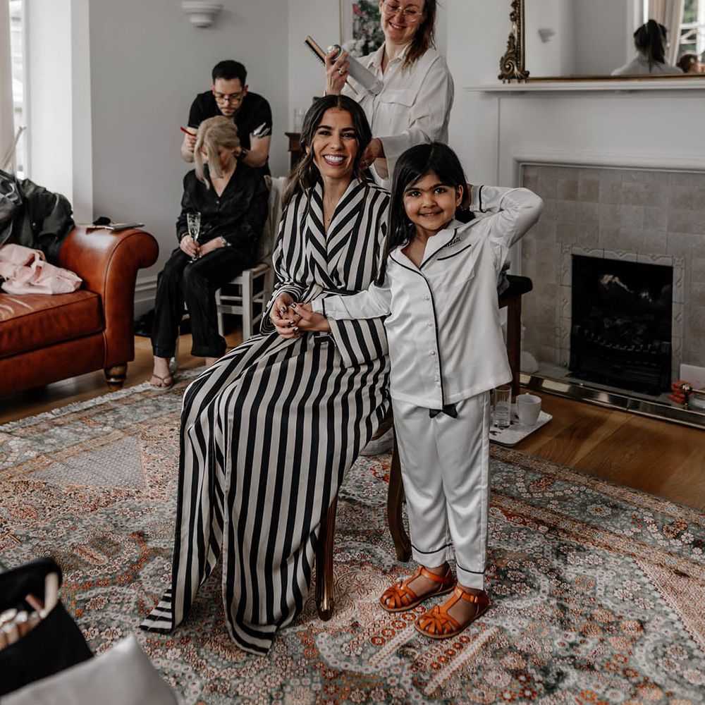 Bride on the wedding morning in a black and white striped robe and flower girl in satin pyjamas 