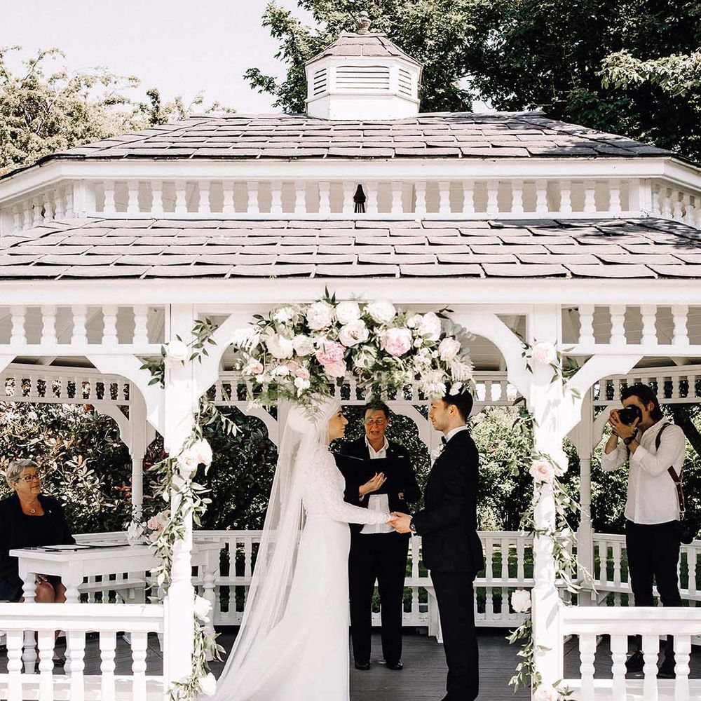 British Muslim bride holding hands with her groom at an outdoor wedding ceremony 