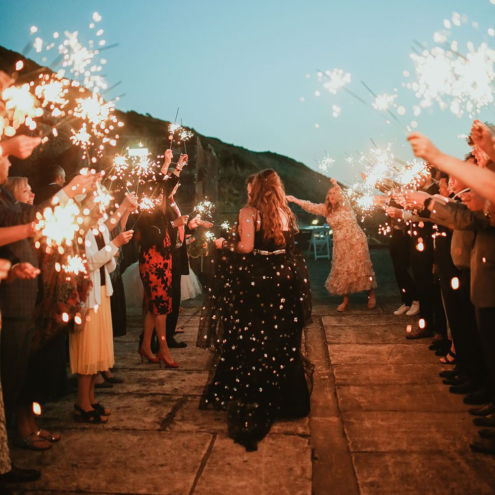 Bride & groom walk through sparkler exit outdoors on their wedding day