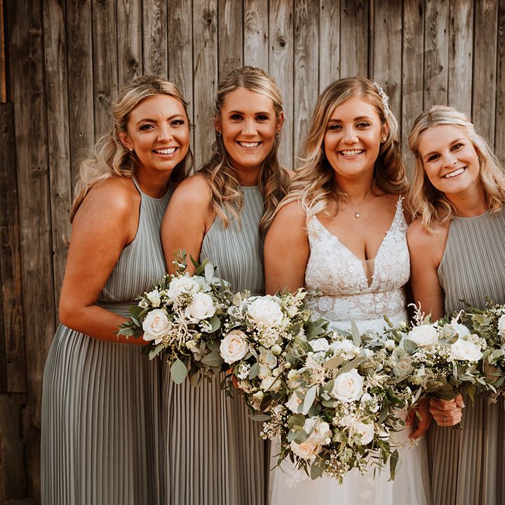 Bride in a lace Christina K wedding dress with the bridesmaids in halter neck sage green pleated bridesmaid dress