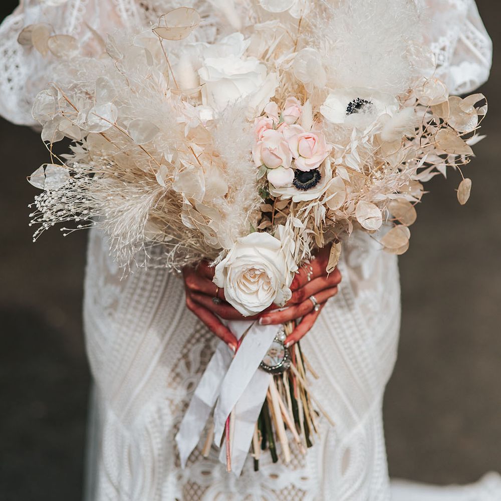 White dried flower wedding bouquet with white poppies, dried grass, and roses 