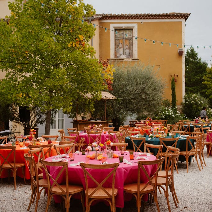 colourful wedding table decorations with pink, orange and green table cloths, taper candles and fruit centrepieces