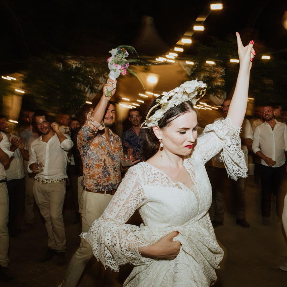 Bride in lace wedding dress, pearl earrings and bridal crown dances at wedding reception in Italy