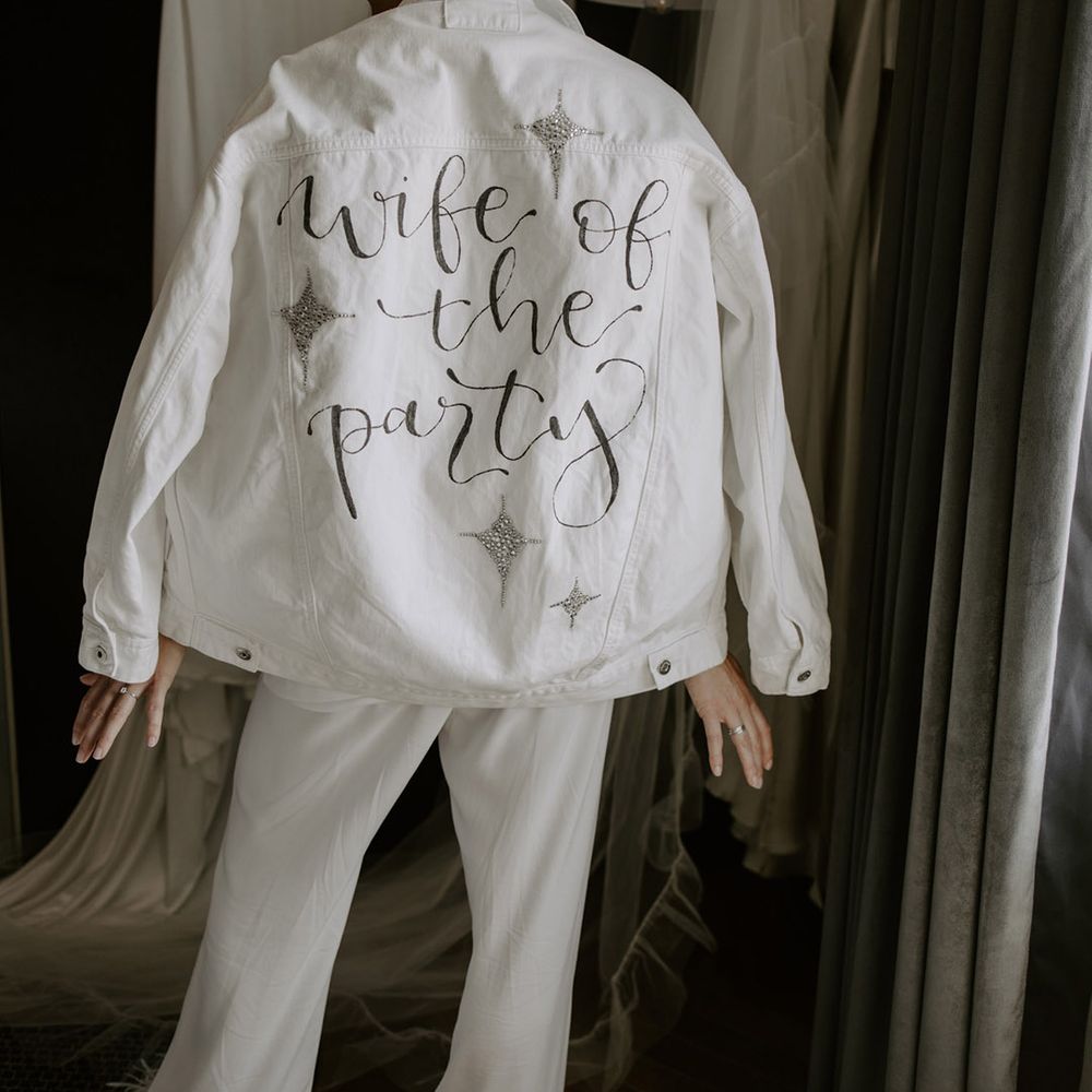 DIY white wedding denim cover-up for the bride with sparkles and hand-painted detail reading 'Wife of the Party' 