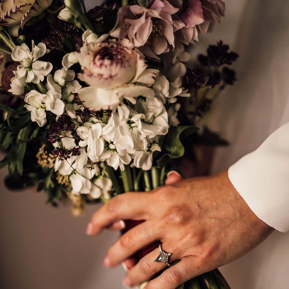 Unique engagement ring holding white and purple wedding bouquet for winter wedding at Pauntley Court