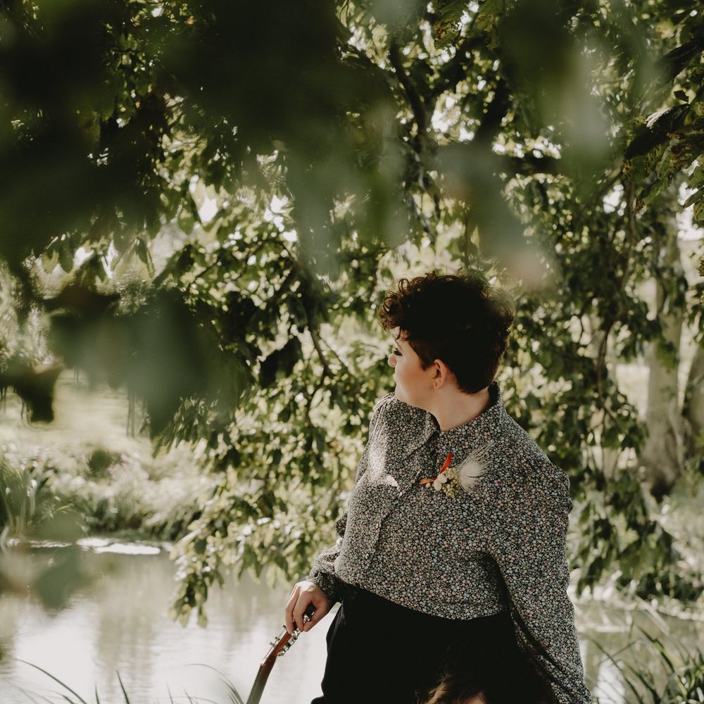 Lesbian couple sitting by the lake in a patterned shirt and jumpsuit 